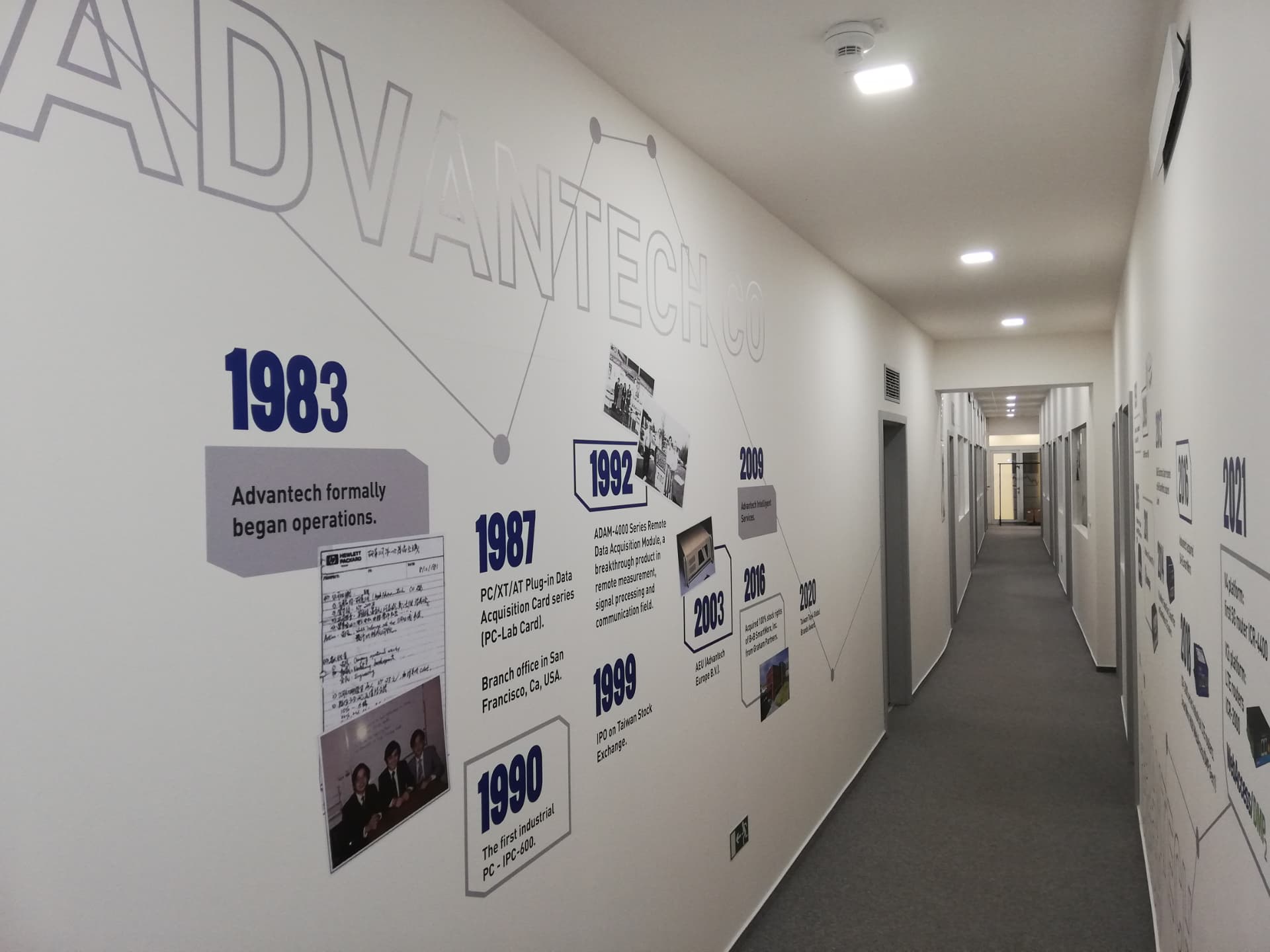 Chodba kanceláří Advantech s firemní časovou osou na stěně